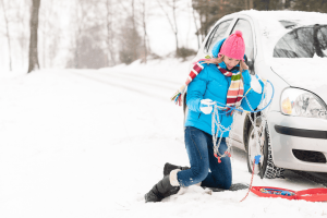 Mujer poniendo cadenas en la nieve